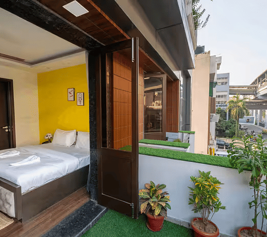 A hotel room with a balcony overlooking the metro line and urban surroundings - Lime Boutique Bed & Breakfast | Nehru Place Metro
